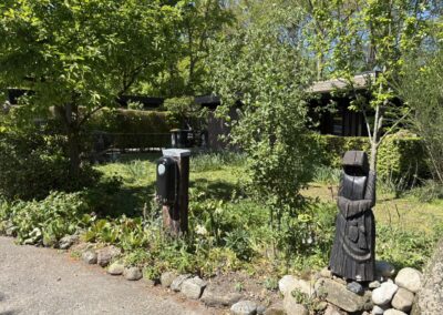 Tuinpad met houten tuinbeeld en laadpaal bij vakantiehuis De Kateeker Ootmarsum