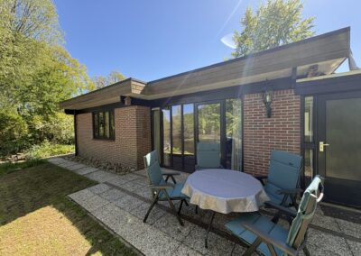 Buitenaanzicht van bungalow De Kateeker in Ootmarsum met terras en tuinstoelen